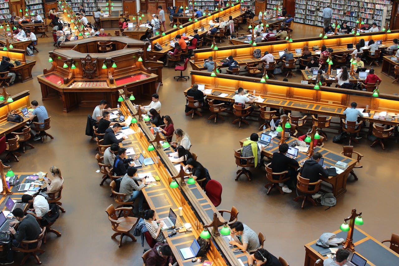 creative-01 A lively university library scene with students studying diligently at wooden desks.