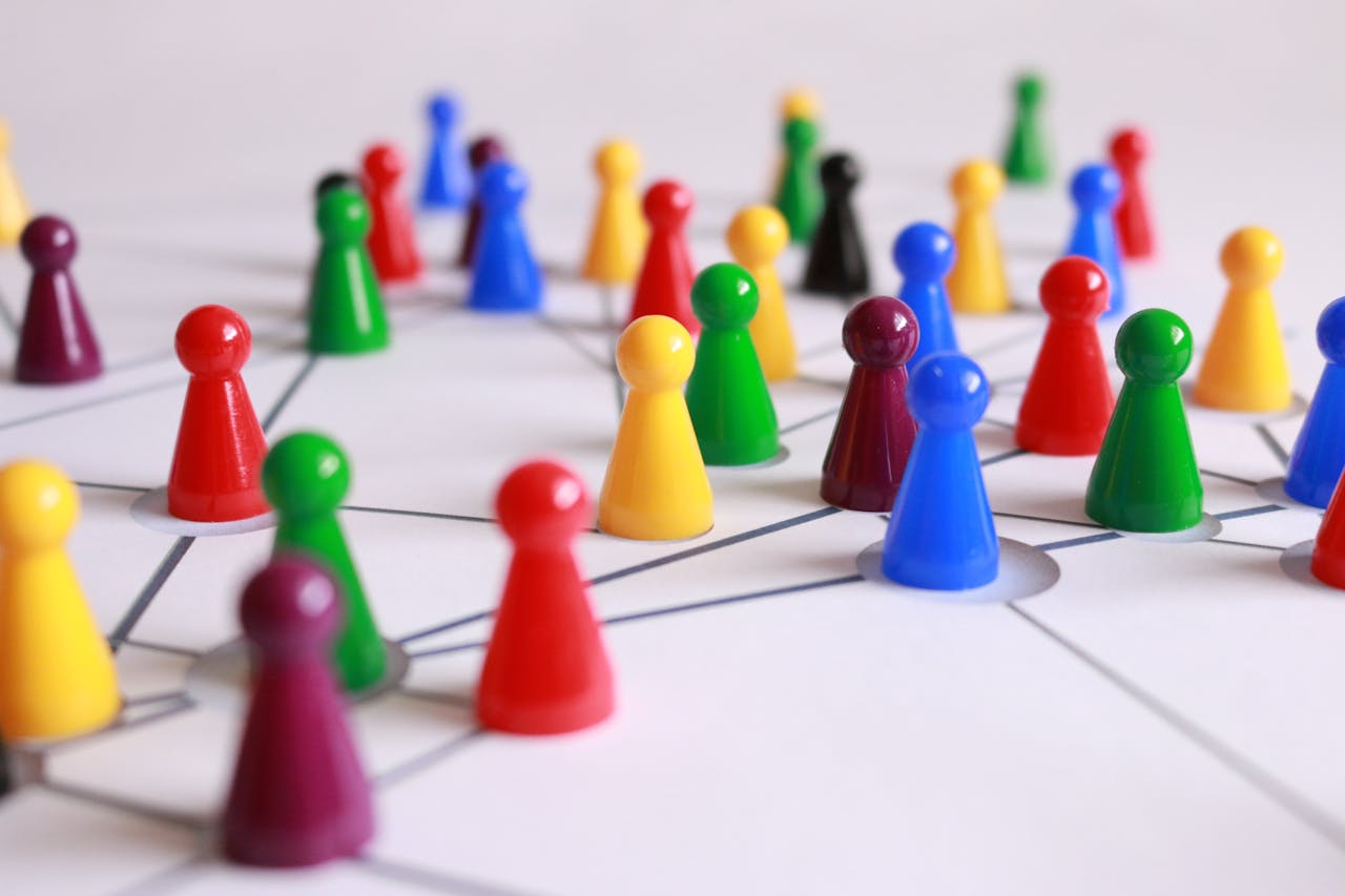 mobile-01 A strategic arrangement of colorful pawns connected on a game board, symbolizing networking and teamwork.